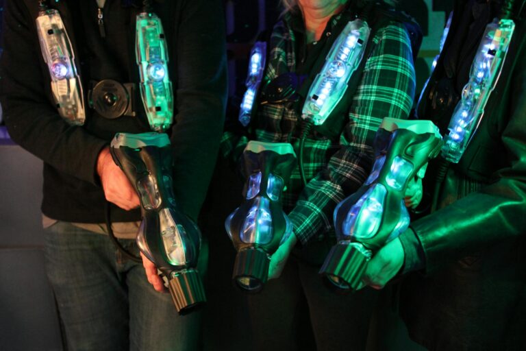 Group playing laser tag with glowing vests indoors. Fun and competitive activity.